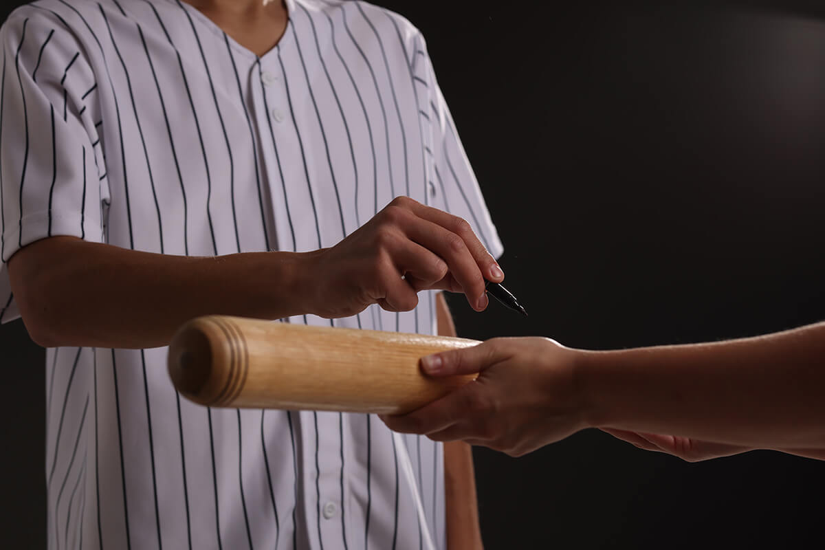 Baseball player signing autograph on bat